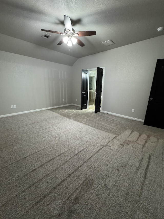 unfurnished bedroom featuring vaulted ceiling, a textured ceiling, carpet floors, and ceiling fan