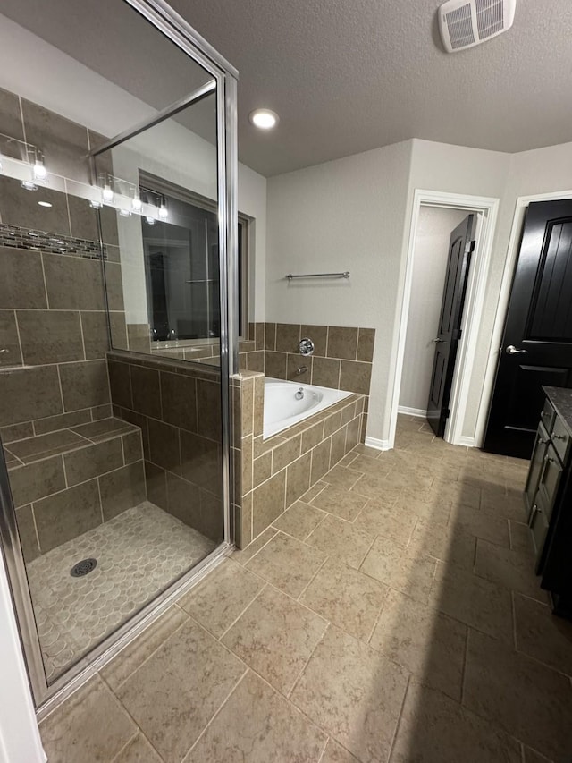 bathroom featuring vanity, a textured ceiling, and plus walk in shower