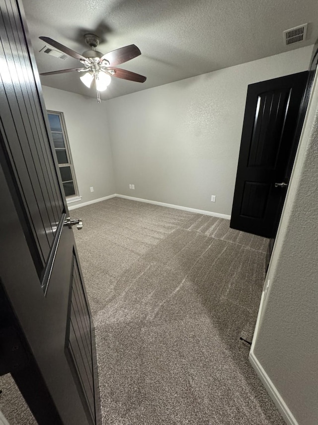 carpeted spare room with a textured ceiling and ceiling fan