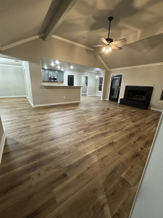 unfurnished living room featuring ornamental molding, ceiling fan, lofted ceiling with beams, and wood-type flooring