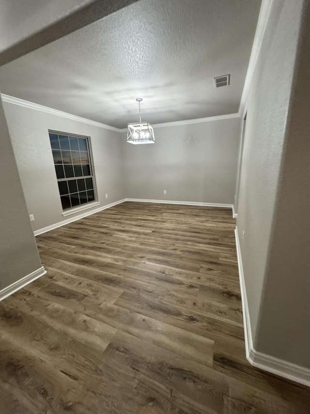 unfurnished dining area featuring ornamental molding, a textured ceiling, and dark hardwood / wood-style floors