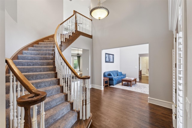 foyer entrance with a towering ceiling and dark hardwood / wood-style floors