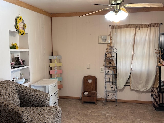 sitting room with ceiling fan, wooden walls, and built in features