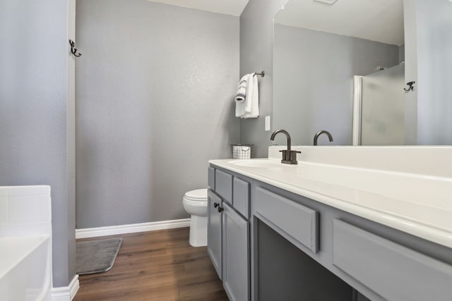 bathroom with toilet, wood-type flooring, vanity, and a bathing tub