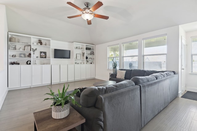 living room with ceiling fan, light hardwood / wood-style flooring, and lofted ceiling