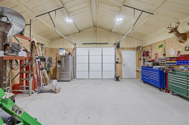 garage featuring stainless steel fridge, a workshop area, and water heater