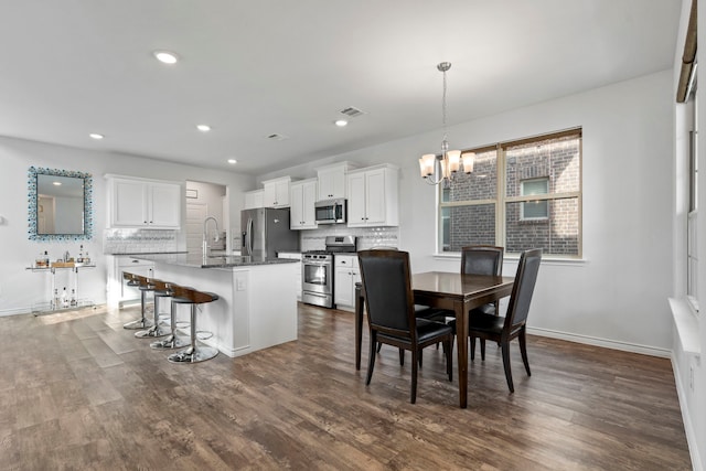 dining space featuring sink, dark hardwood / wood-style flooring, and an inviting chandelier