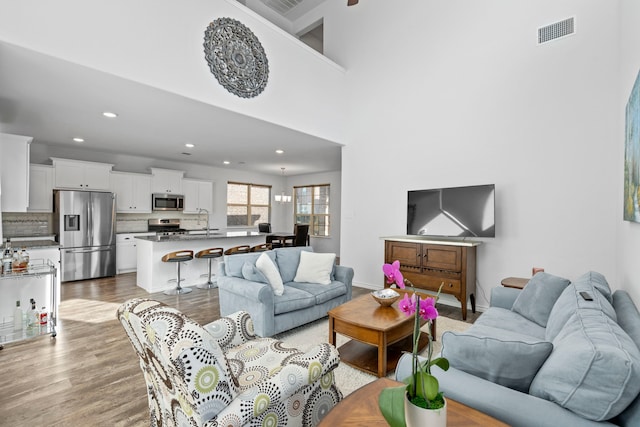 living room featuring a high ceiling, light hardwood / wood-style floors, and sink