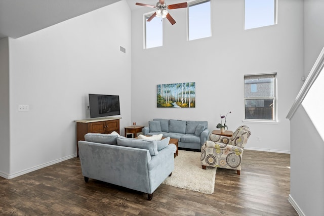 living room featuring a towering ceiling, dark wood-type flooring, and ceiling fan