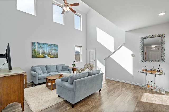 living room featuring a towering ceiling, hardwood / wood-style floors, ceiling fan, and a wealth of natural light