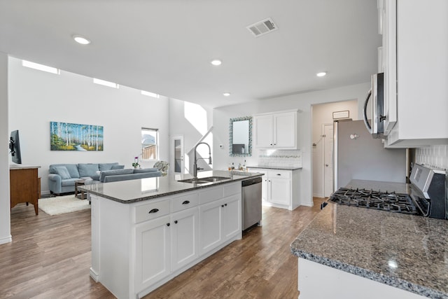 kitchen featuring stainless steel appliances, white cabinetry, an island with sink, and sink