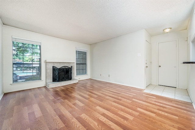 unfurnished living room with a textured ceiling, light wood-type flooring, and a tile fireplace