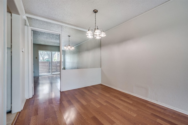 unfurnished dining area featuring a textured ceiling, crown molding, a chandelier, and wood-type flooring