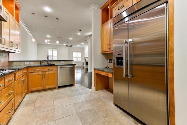 kitchen featuring kitchen peninsula, stainless steel appliances, dark stone countertops, ceiling fan, and sink