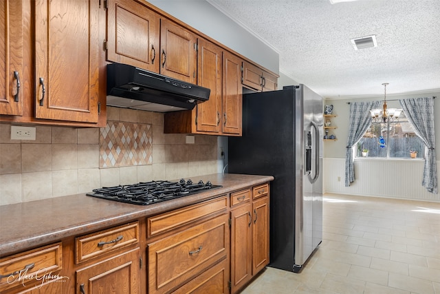 kitchen featuring a textured ceiling, hanging light fixtures, black gas stovetop, stainless steel fridge, and a notable chandelier