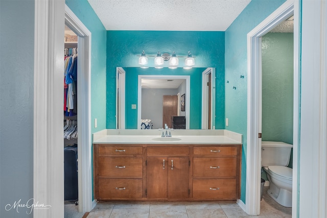 bathroom with toilet, tile patterned flooring, vanity, and a textured ceiling