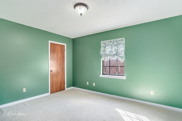 carpeted empty room featuring a textured ceiling