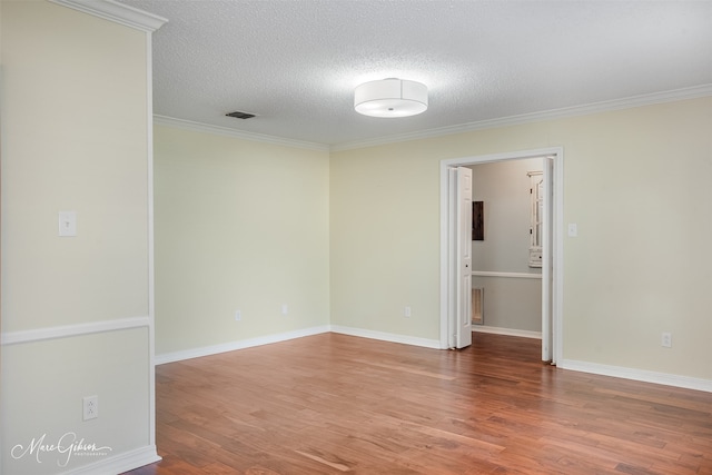 empty room with ornamental molding, a textured ceiling, and hardwood / wood-style flooring