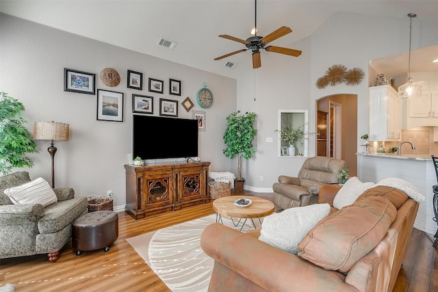 living room featuring sink, wood-type flooring, ceiling fan, and vaulted ceiling