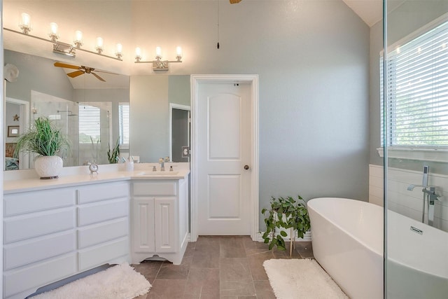 bathroom featuring vanity, a wealth of natural light, vaulted ceiling, and a bathing tub