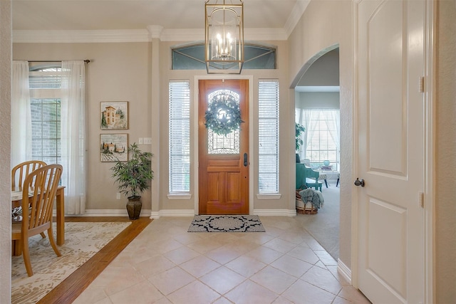 tiled foyer with ornamental molding and a notable chandelier