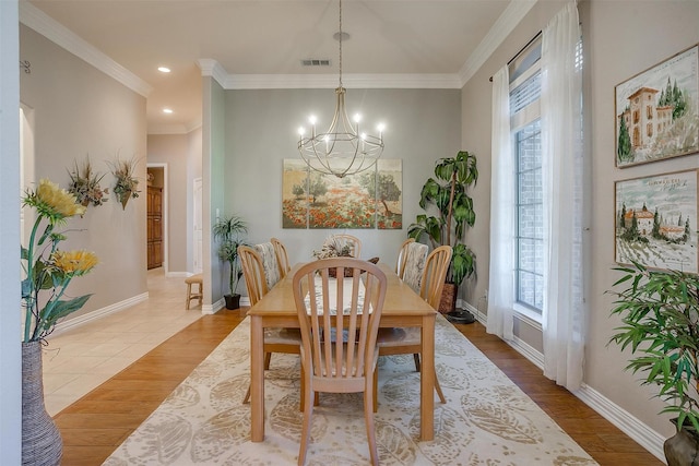 dining room with a notable chandelier, light wood-type flooring, and crown molding