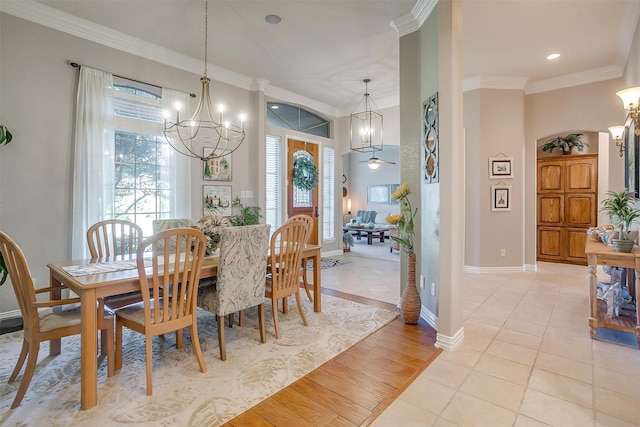 tiled dining space with ornamental molding and ceiling fan with notable chandelier