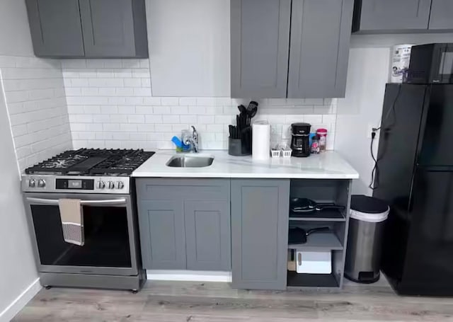 kitchen featuring stainless steel gas stove, gray cabinets, and tasteful backsplash