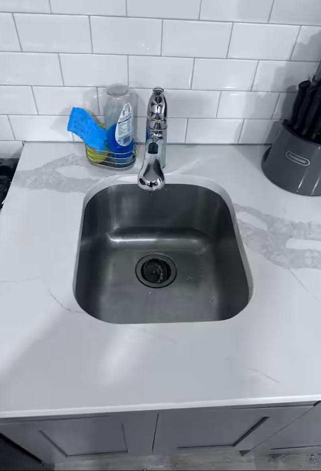 room details with sink, light stone counters, and gray cabinets