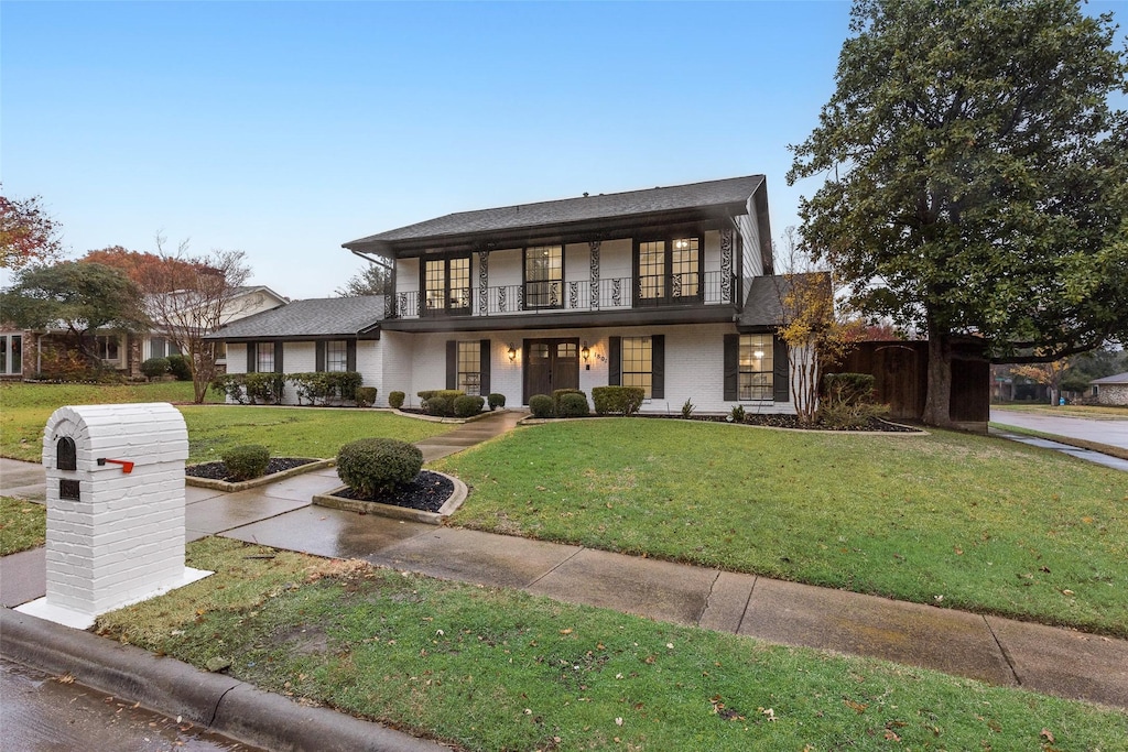 view of front of home with a balcony and a front lawn