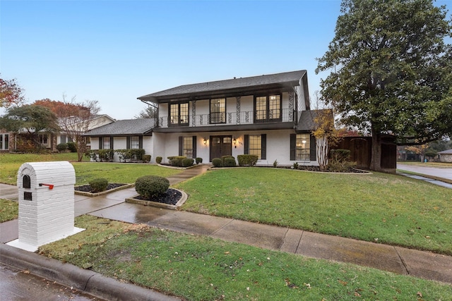 view of front of home with a balcony and a front lawn