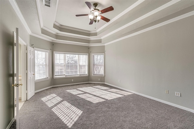 carpeted empty room featuring ceiling fan, crown molding, a raised ceiling, and a wealth of natural light