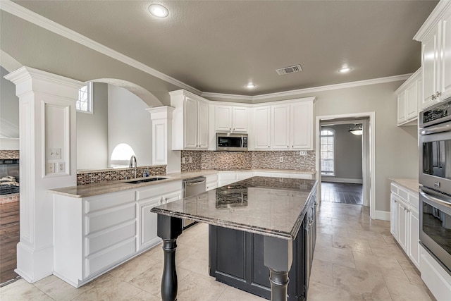 kitchen with a center island, white cabinetry, stone counters, appliances with stainless steel finishes, and sink