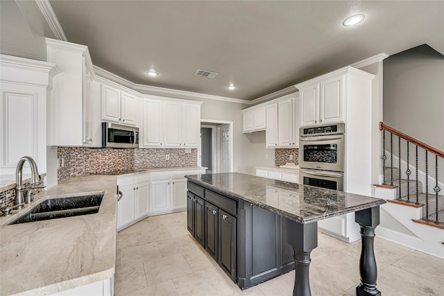 kitchen with appliances with stainless steel finishes, dark stone counters, white cabinetry, and sink