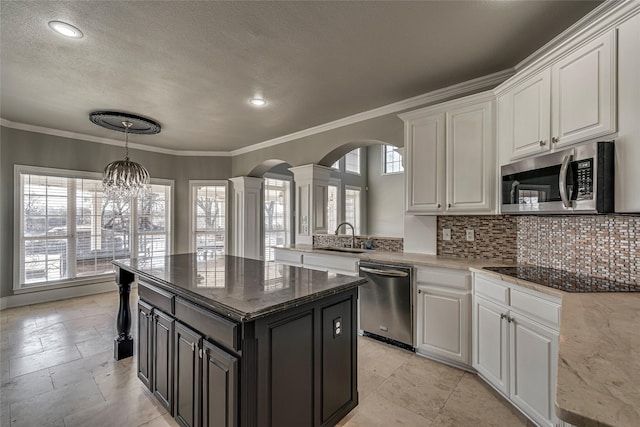 kitchen with a kitchen island, decorative columns, white cabinets, appliances with stainless steel finishes, and sink