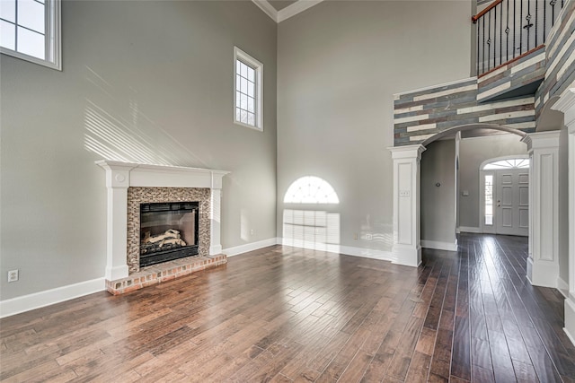 unfurnished living room with a towering ceiling, decorative columns, and dark hardwood / wood-style floors