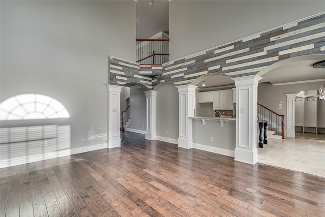 unfurnished living room with a high ceiling, wood-type flooring, and ornamental molding