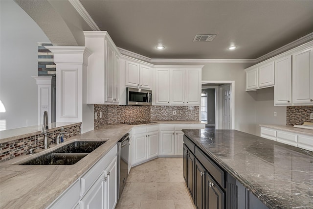 kitchen featuring stainless steel appliances, white cabinets, sink, and dark stone counters