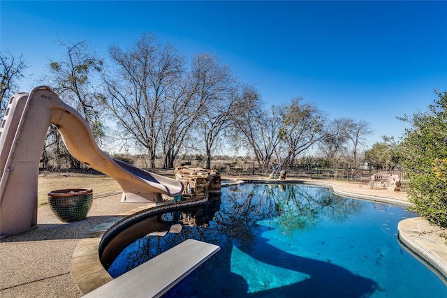 view of pool featuring a diving board and a water slide