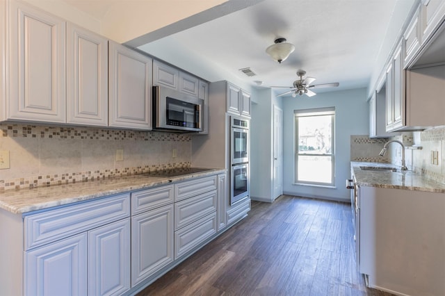 kitchen featuring appliances with stainless steel finishes, ceiling fan, dark hardwood / wood-style flooring, sink, and tasteful backsplash