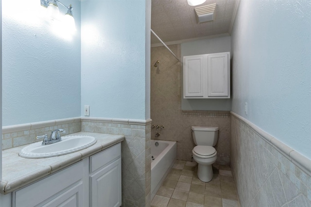 full bathroom featuring toilet, tub / shower combination, vanity, ornamental molding, and tile walls