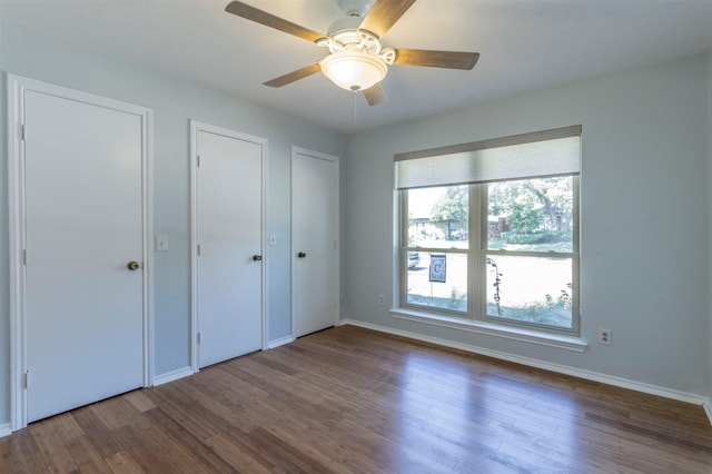 unfurnished bedroom with ceiling fan, wood-type flooring, and multiple windows