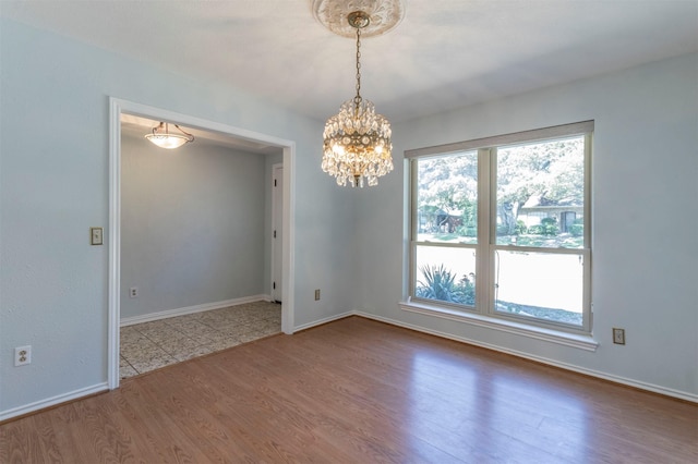 spare room with an inviting chandelier and hardwood / wood-style floors