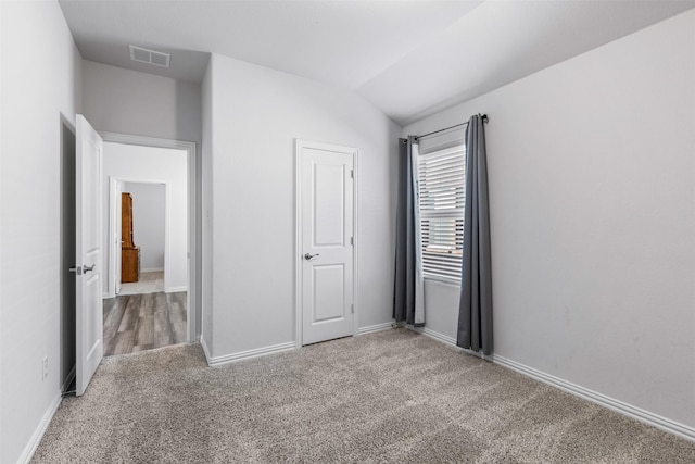 unfurnished bedroom with vaulted ceiling and carpet flooring