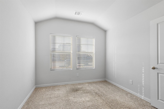 carpeted spare room with lofted ceiling