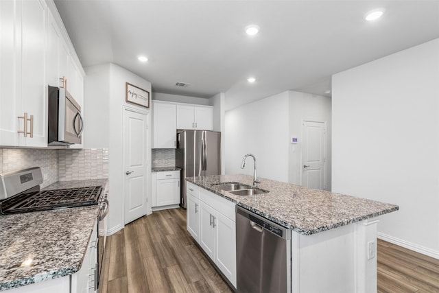 kitchen with appliances with stainless steel finishes, white cabinets, a kitchen island with sink, and sink