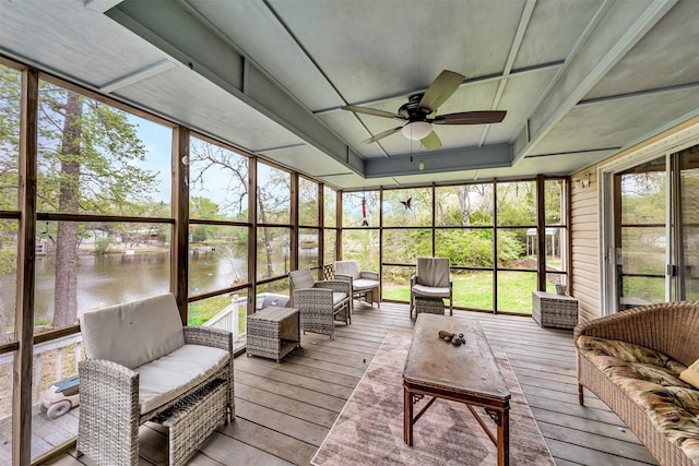 sunroom with ceiling fan and a water view