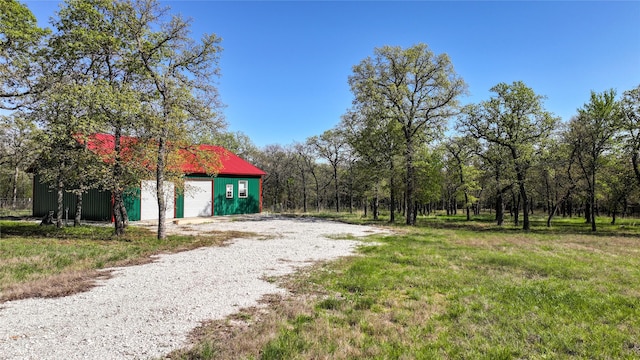 view of yard featuring an outdoor structure and gravel driveway