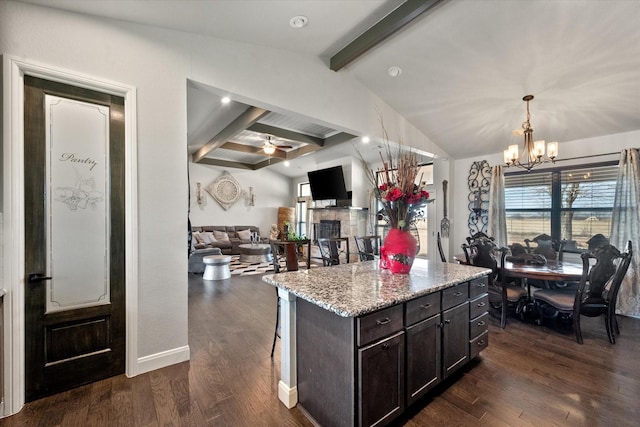 kitchen with light stone countertops, a kitchen island, dark wood-style floors, and dark brown cabinets