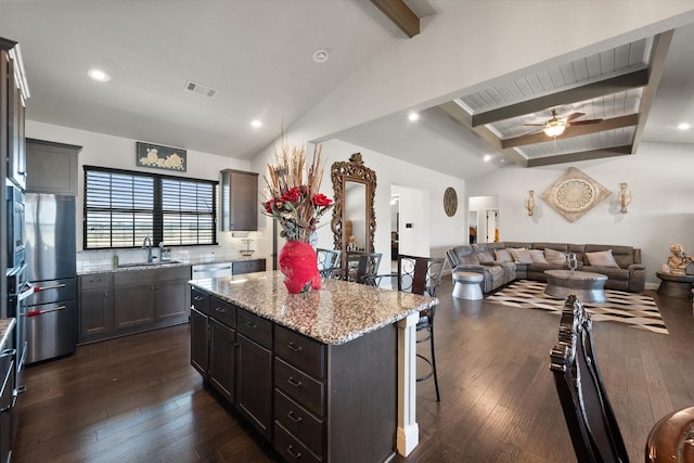 kitchen featuring lofted ceiling with beams, dark wood-style flooring, open floor plan, a center island, and a kitchen bar